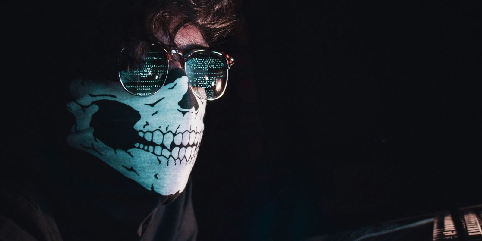 149M logins exposed in unsecured database, inc 900k Apple IDs | Image shows a masked man with code reflected in his glasses