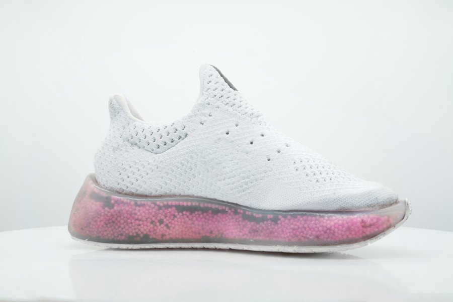 White running shoe with a transparent midsole filled with pink and black plastic balls