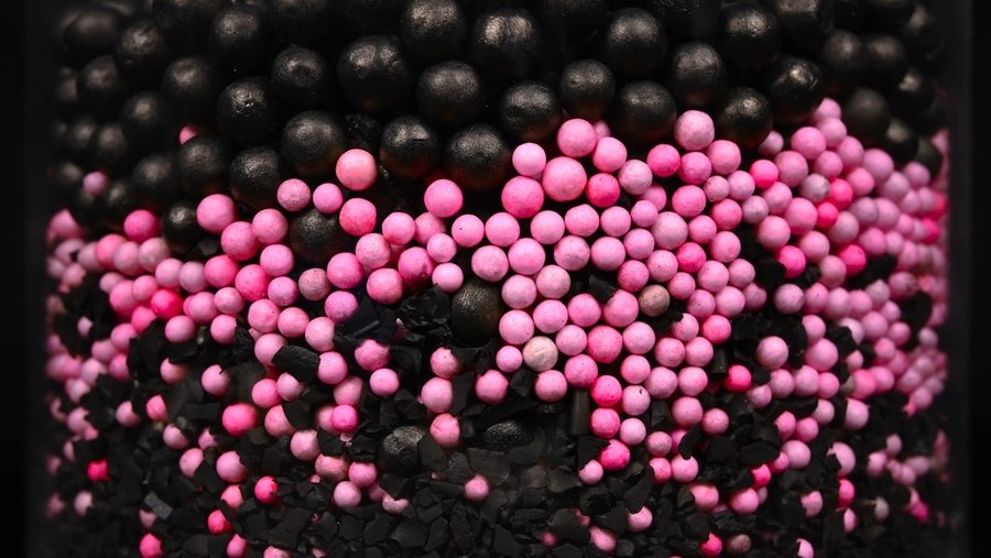 Closeup photo of a mix of small pink plastic balls and larger black plastic balls