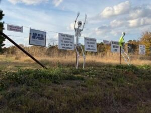 Signs of opposition to the Franklin County prison decorated the fence directly across the street from the prison site's entrance on Arkansas Highway 215 on Nov. 13, 2025. (Photo by Ainsley Platt/Arkansas Advocate)
