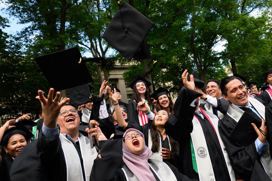 Graduates in caps and gowns celebrate, throwing caps in the air