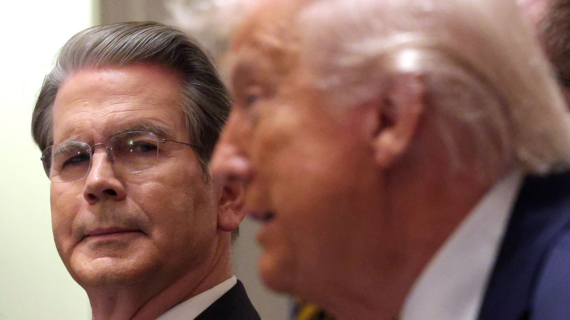 Scott Bessent is shown close-up and in focus, with President Trump in the foreground.