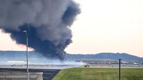 Getty Images A large plume of dark grey smoke marks where a UPS cargo plane crashed near Louisville Muhammad Ali International Airport on 4 November 2025