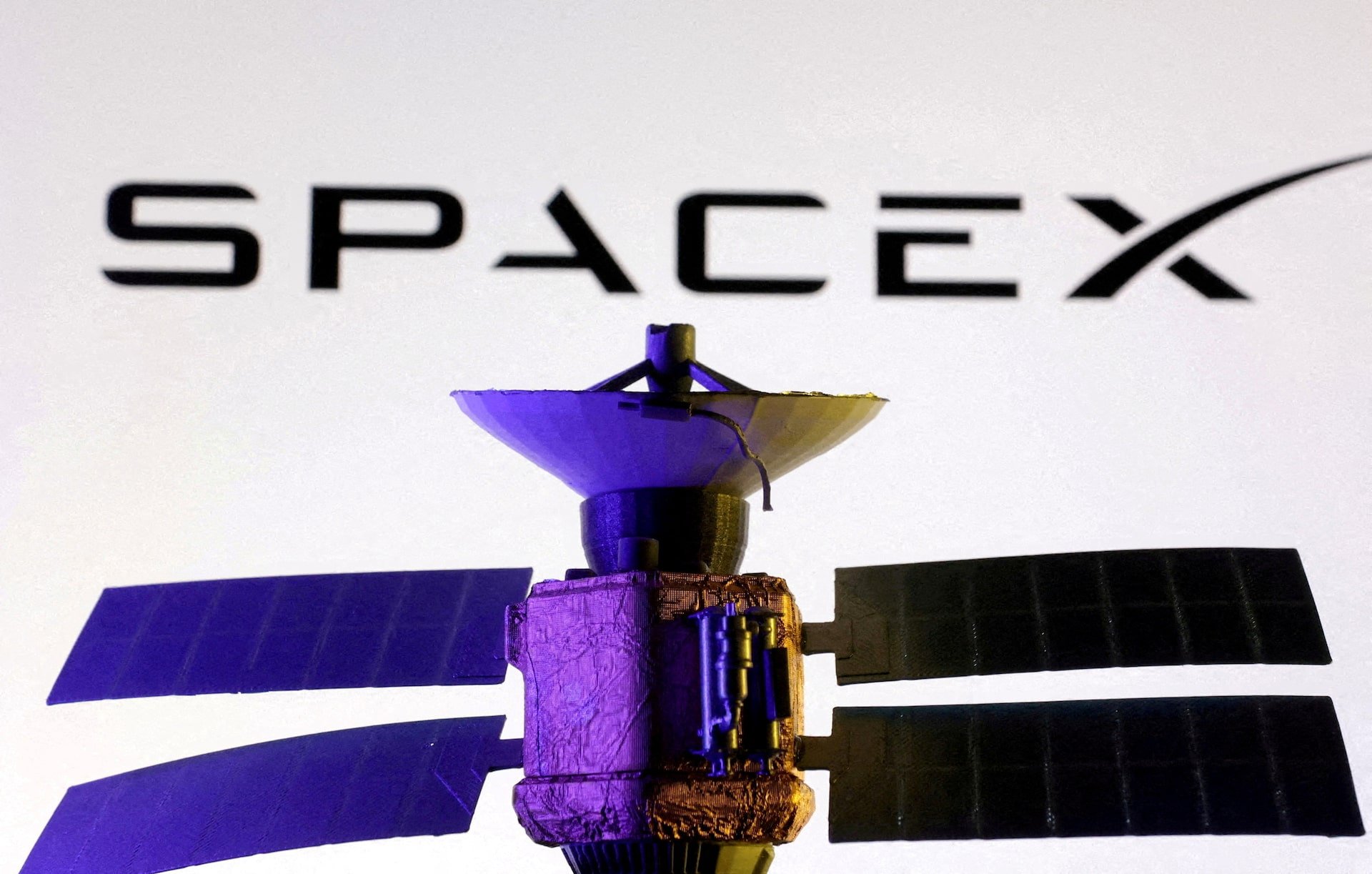 Illustration shows SpaceX logo and miniature satellite model