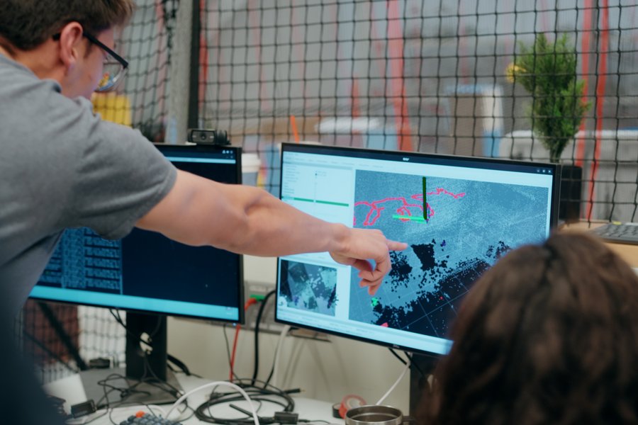 Student pictured from behind pointing at data on a computer screen