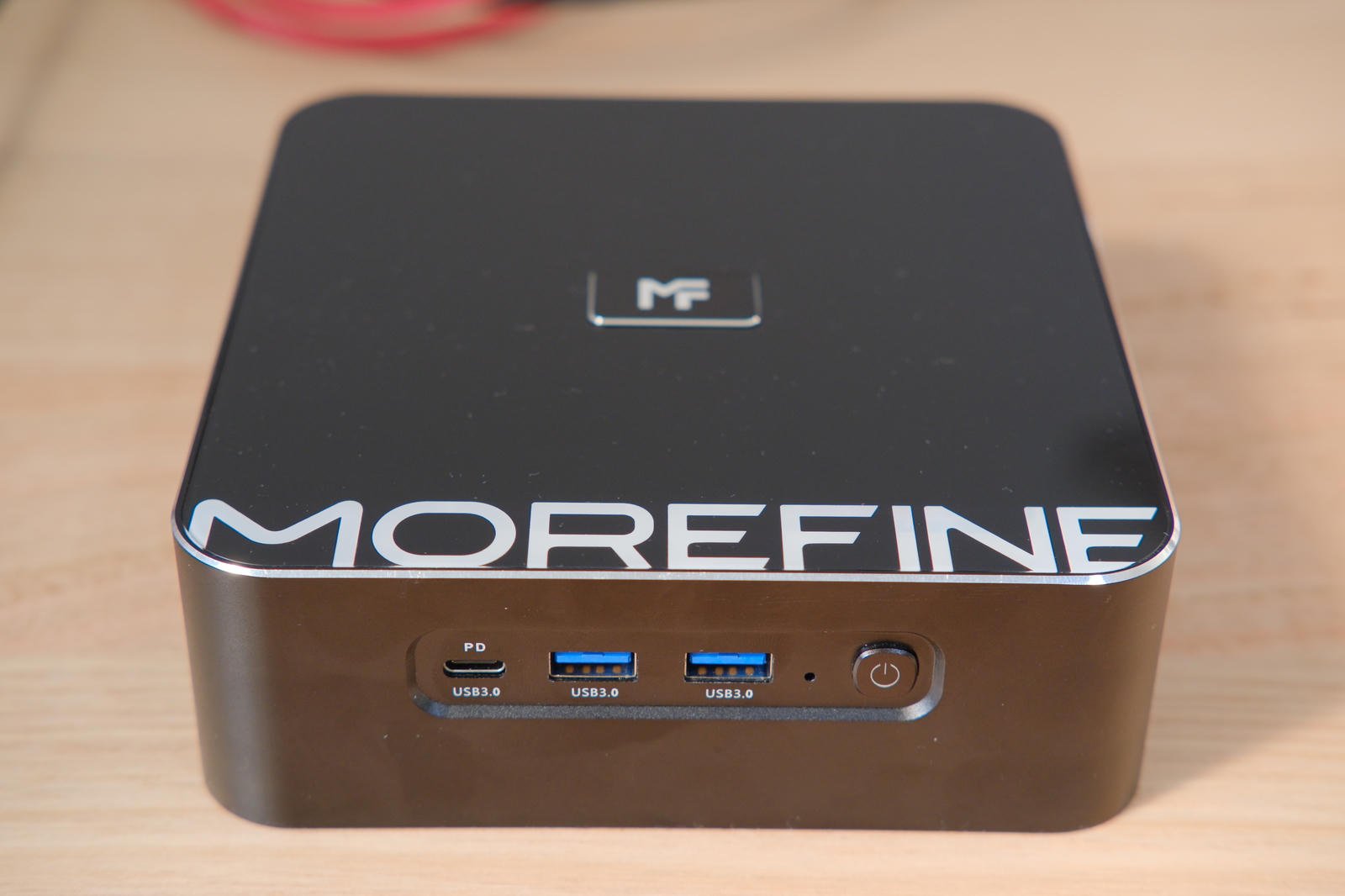 Photo of the top and front of the M700S. It's a small black computer with a Type-C and two Type-A USB ports on the front along with a power button.