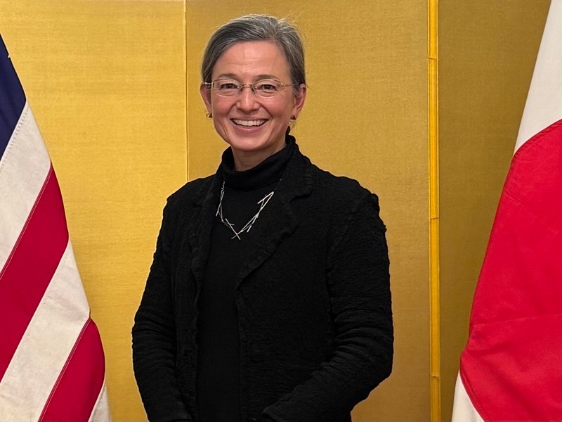 Christine Pilcavage poses standing between an American flag and a Japanese flag