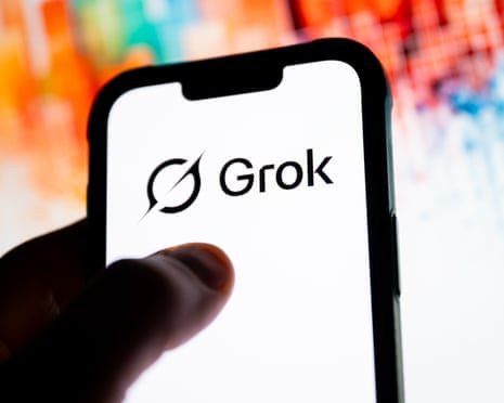 Person holds a phone with Grok logo displayed on screen.