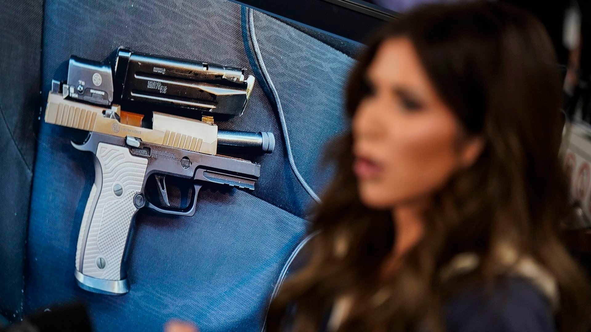 Homeland Security Secretary Kristi Noem at FEMA headquarters with a display of the pistol recovered in Minneapolis behind her, where federal agents fatally shot ICU nurse Alex Pretti.