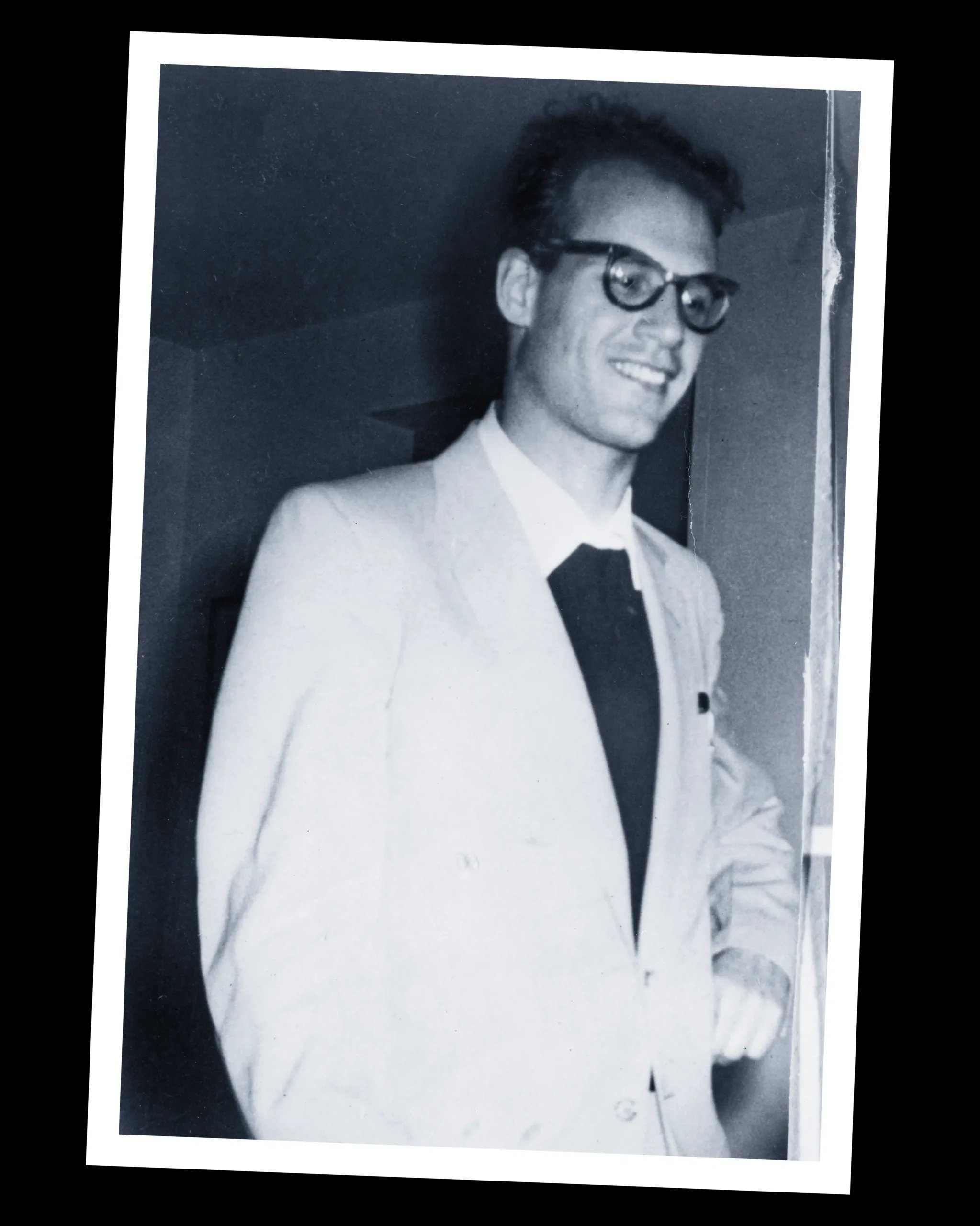 A smiling young man with glasses and a suit