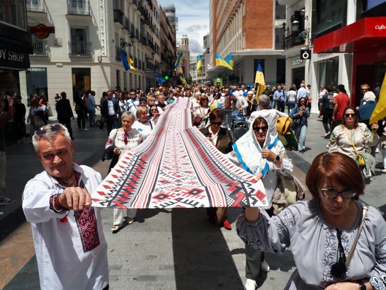 Members of the Ukrainian community in Spain taking part in a procession through the streets of Madrid carrying a long embroidered piece of cloth.