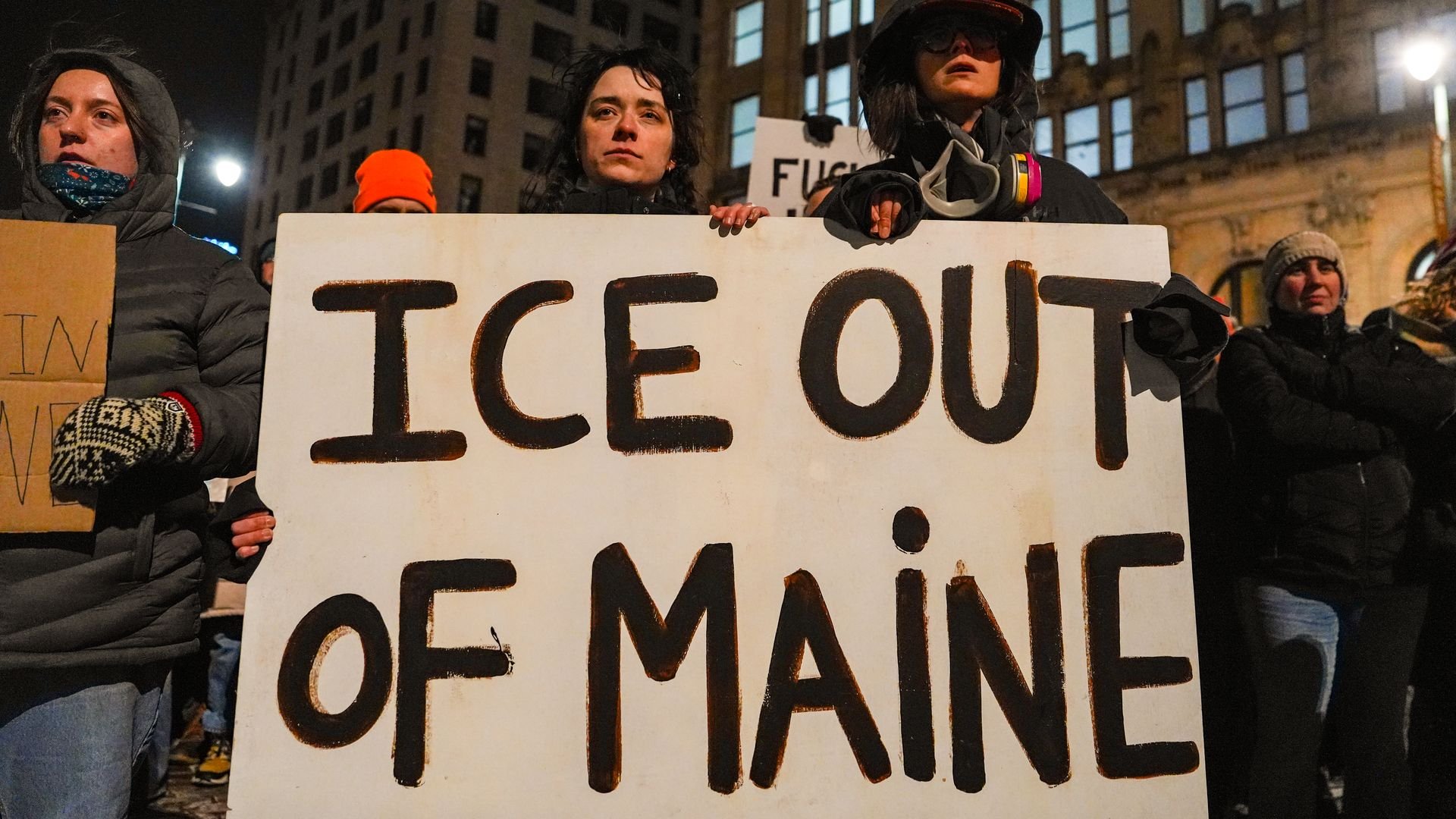 A group of protesters gather outdoors in Portland, Maine, holding signs and chanting during an anti-Immigration and Customs Enforcement demonstration.