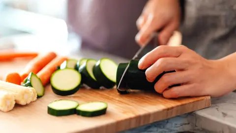 Getty Images A person at home chops a courgette on a wooden chopping board
