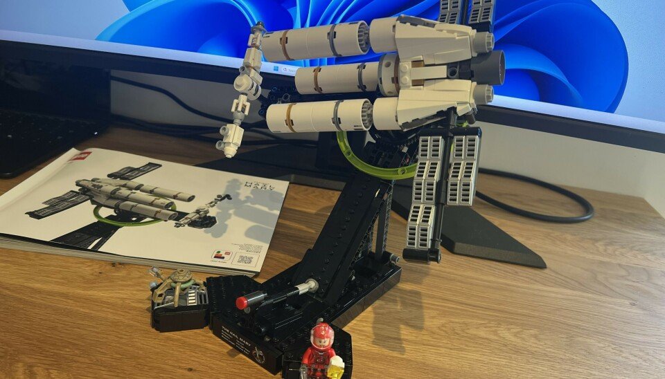 A Lego Technic spacecraft model displayed on a desk beside an instruction booklet and a small minifigure.