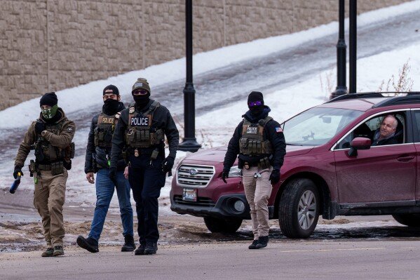 A person looks out of their vehicle as Immigration and Customs Enforcement (ICE) agents walk away, Thursday, Jan. 15, 2026, in Richfield, Minn. (AP Photo/Adam Gray)