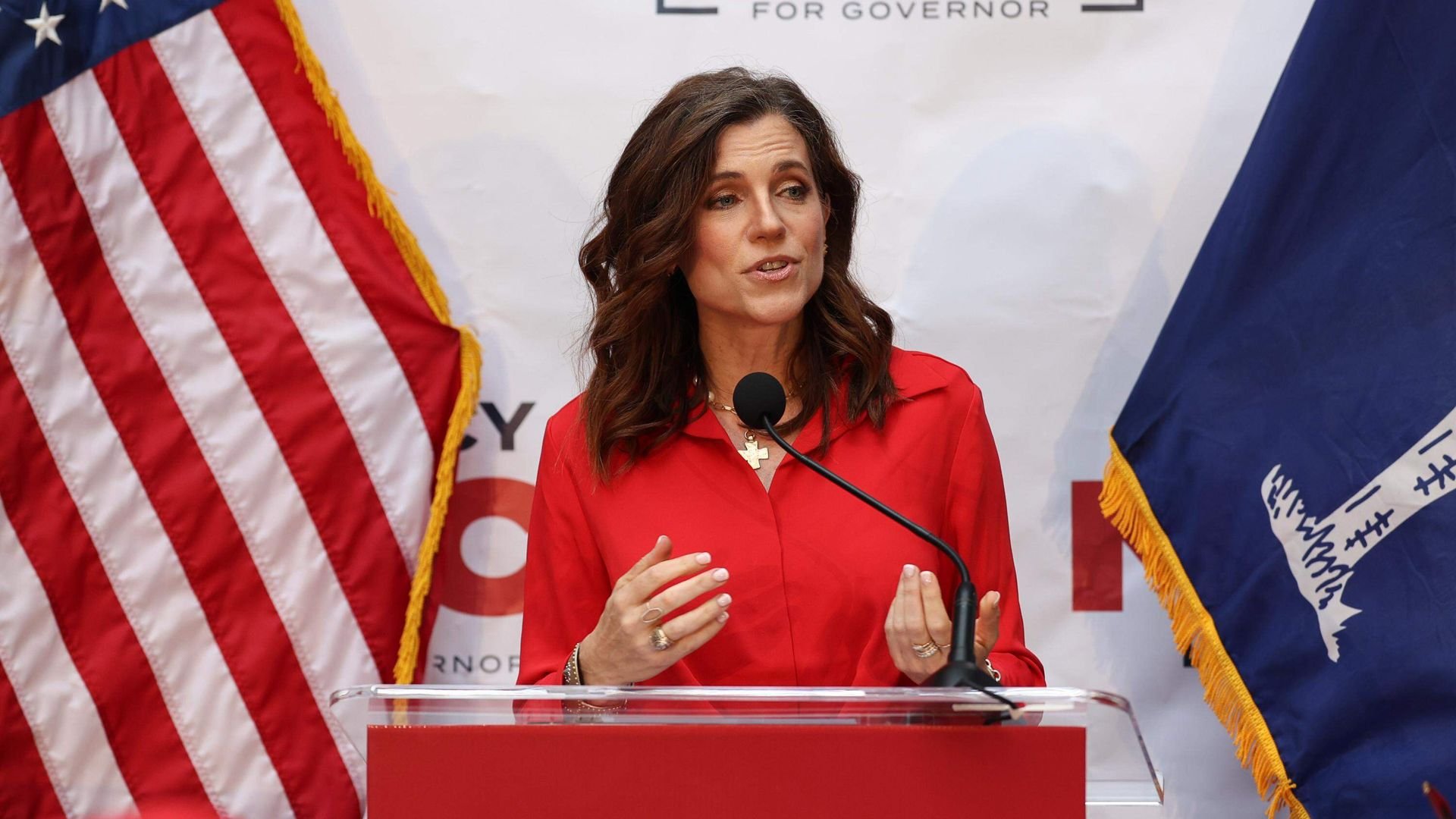Woman in red shirt speaking at podium with 