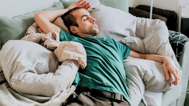 A young man on the couch in an awkward-looking sitting position