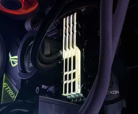 An image of an RGB DDR4 RAM kit installed on a motherboard illuminated in a yellow glow. 