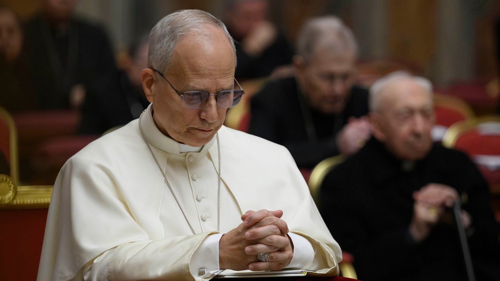 Pope Leo XIV with his hands crossed looking down in prayer