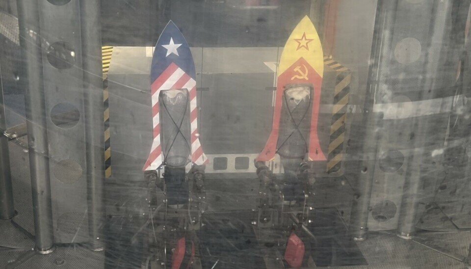 Two decorated bottle rockets on stands behind glass in an indoor science exhibit.