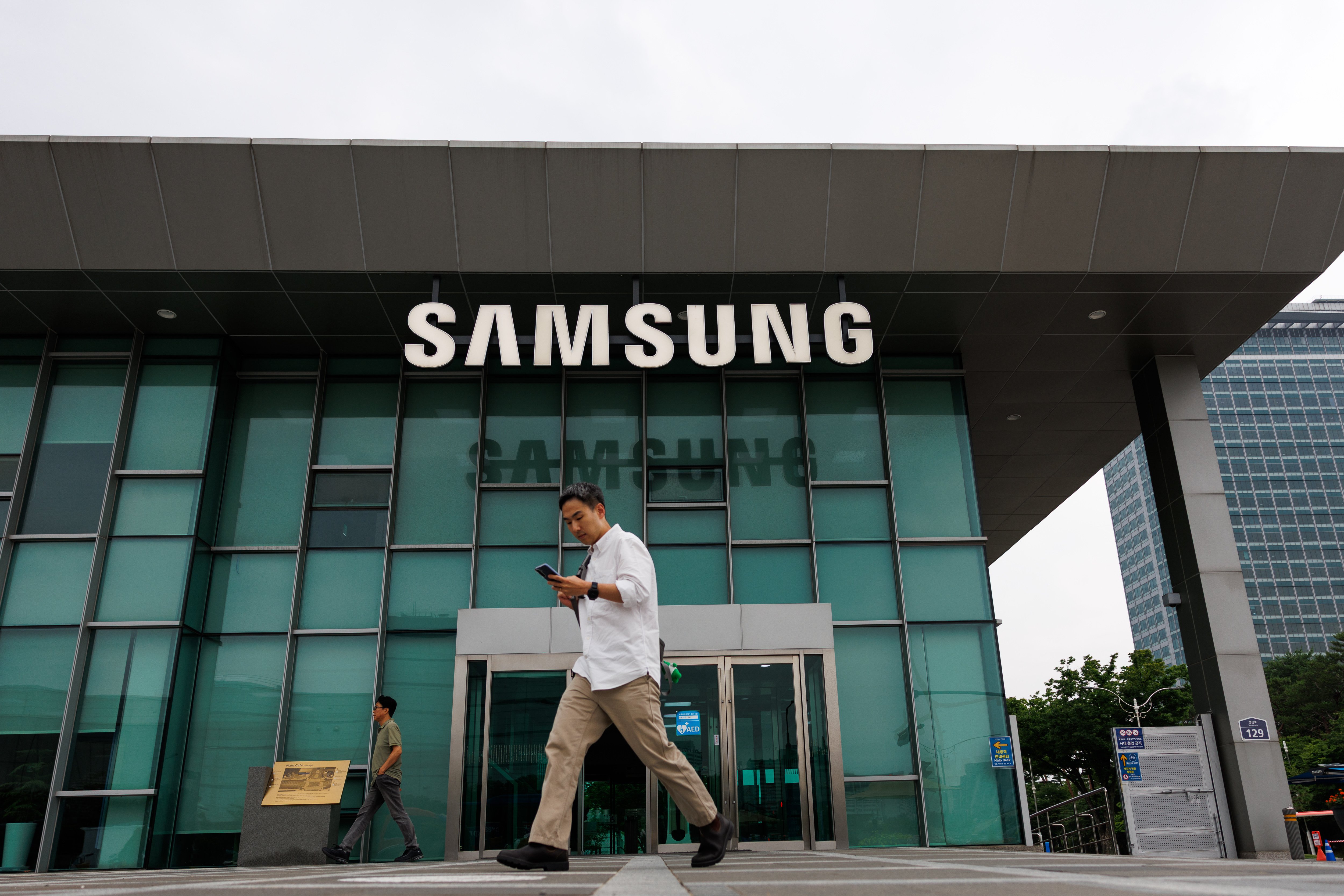 Samsung HQ, with a man on a cell phone seen walking in front of the building to the left.