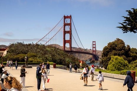 people walk outside near a red bridge