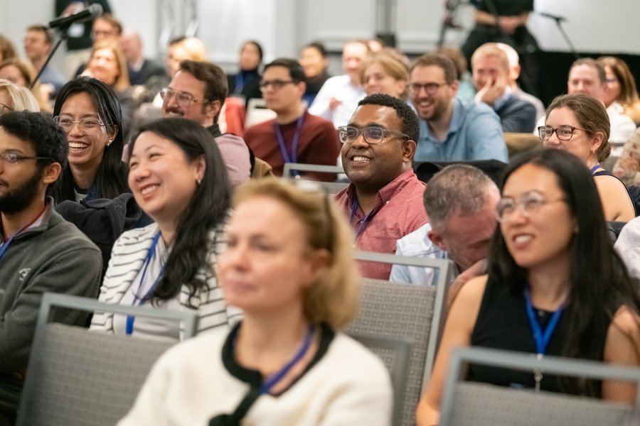About 30 audience members sitting in rows are smiling and laughing