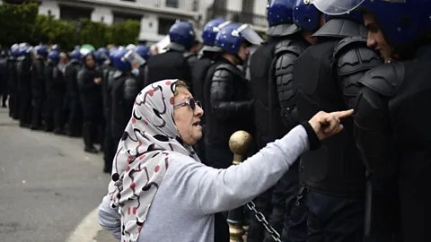 Getty Images An elderly woman talks to the Algerian security forces during the recent protests (Credit: Getty Images)