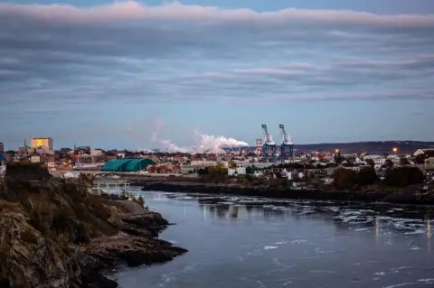 A look at the industrial port in the city of Saint John, New Brunswick, with the river and sky both prominent.