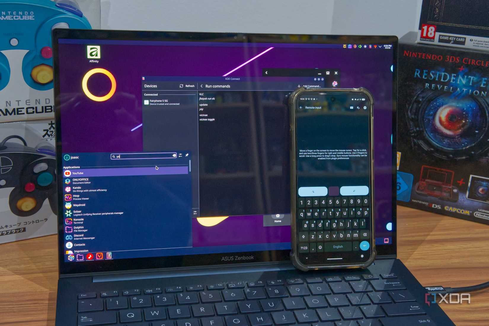 A laptop showing KDE Connect and an application launcher, next to a phone being used to remotely control the computer