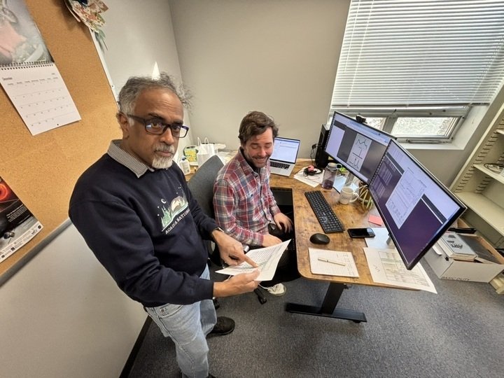Ganesh Rajagopalan and Dan Hoak look at a piece of paper in a small office