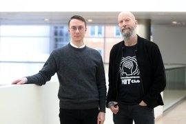 Matthias Michel and Earl Miller pose together on the balcony of an atrium