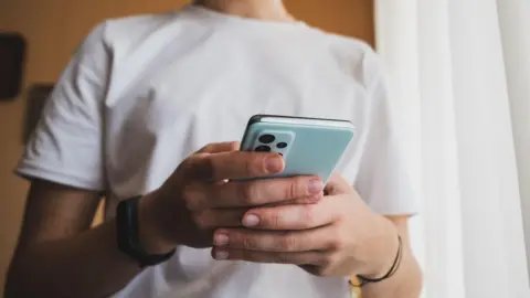 Getty Images A close-up of hands using a blue smartphone