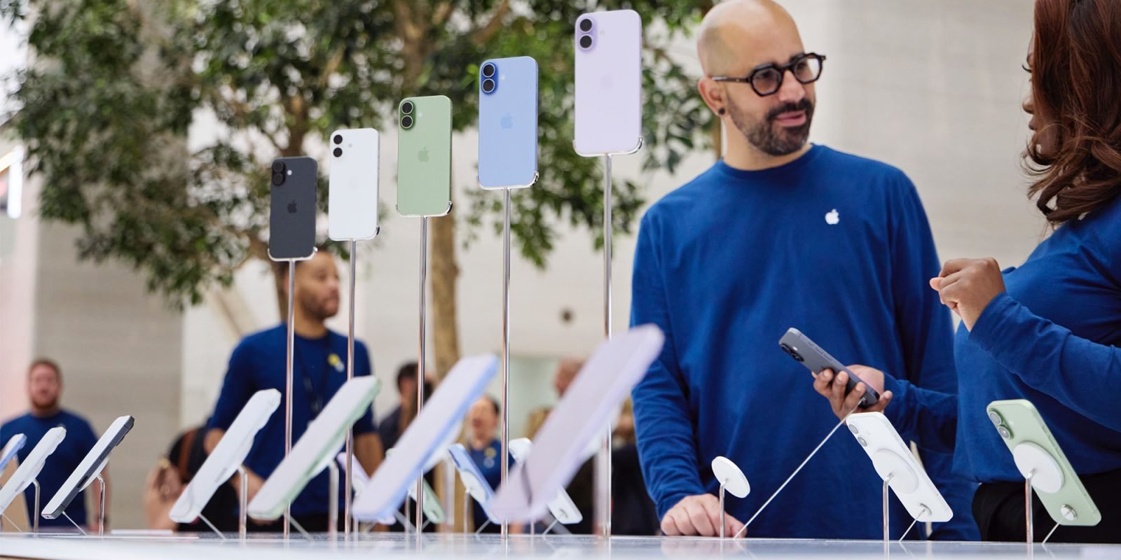 Tim Cook didn't rule out price rises for Apple products, and this is the reason | Photo shows staff chatting behind a display of iPhones at an Apple store