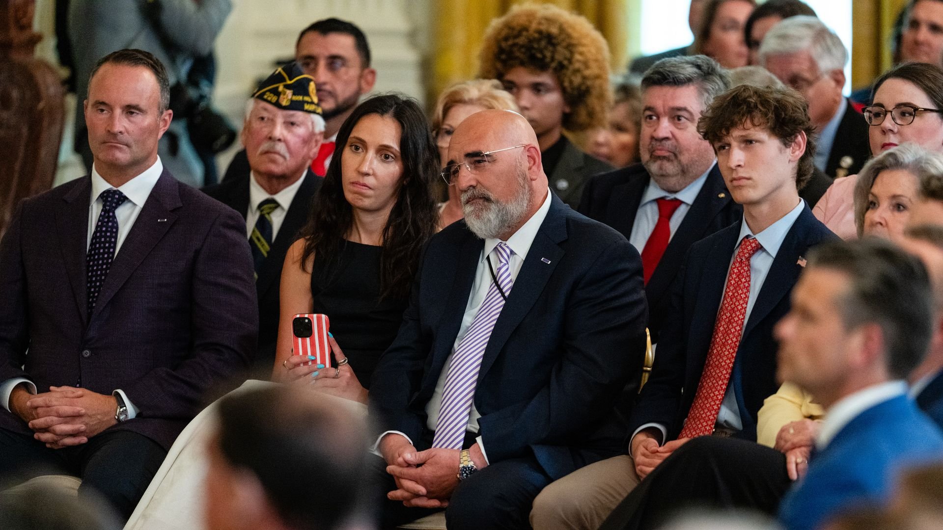 Man folds hands in crowd seated