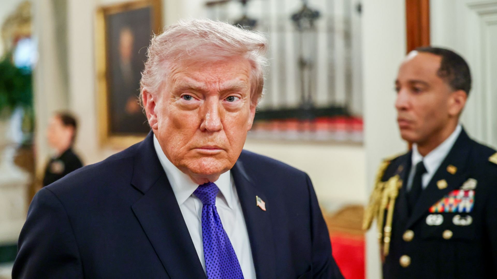 Trump wearing a navy suit jacket, white shirt and purple tie