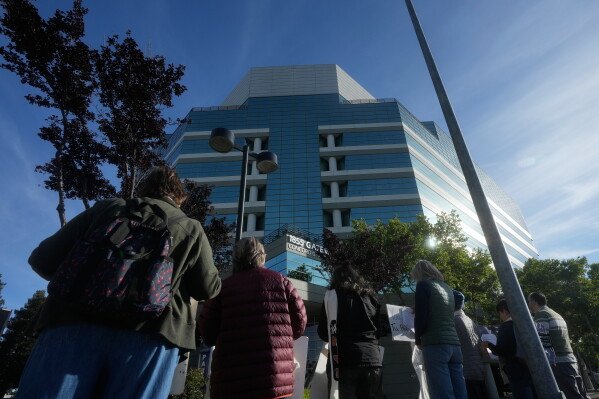 An interfaith community group holds signs while singing outside of Immigration Court Tuesday, May 12, 2026, in Concord, Calif. (AP Photo/Jeff Chiu)