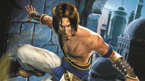 Ubisoft A video game character wearing garb referencing historic Middle Eastern attire. He has blue eyes and a long brown fringe. In the background, a city scene with buildings in a historic Persian style.