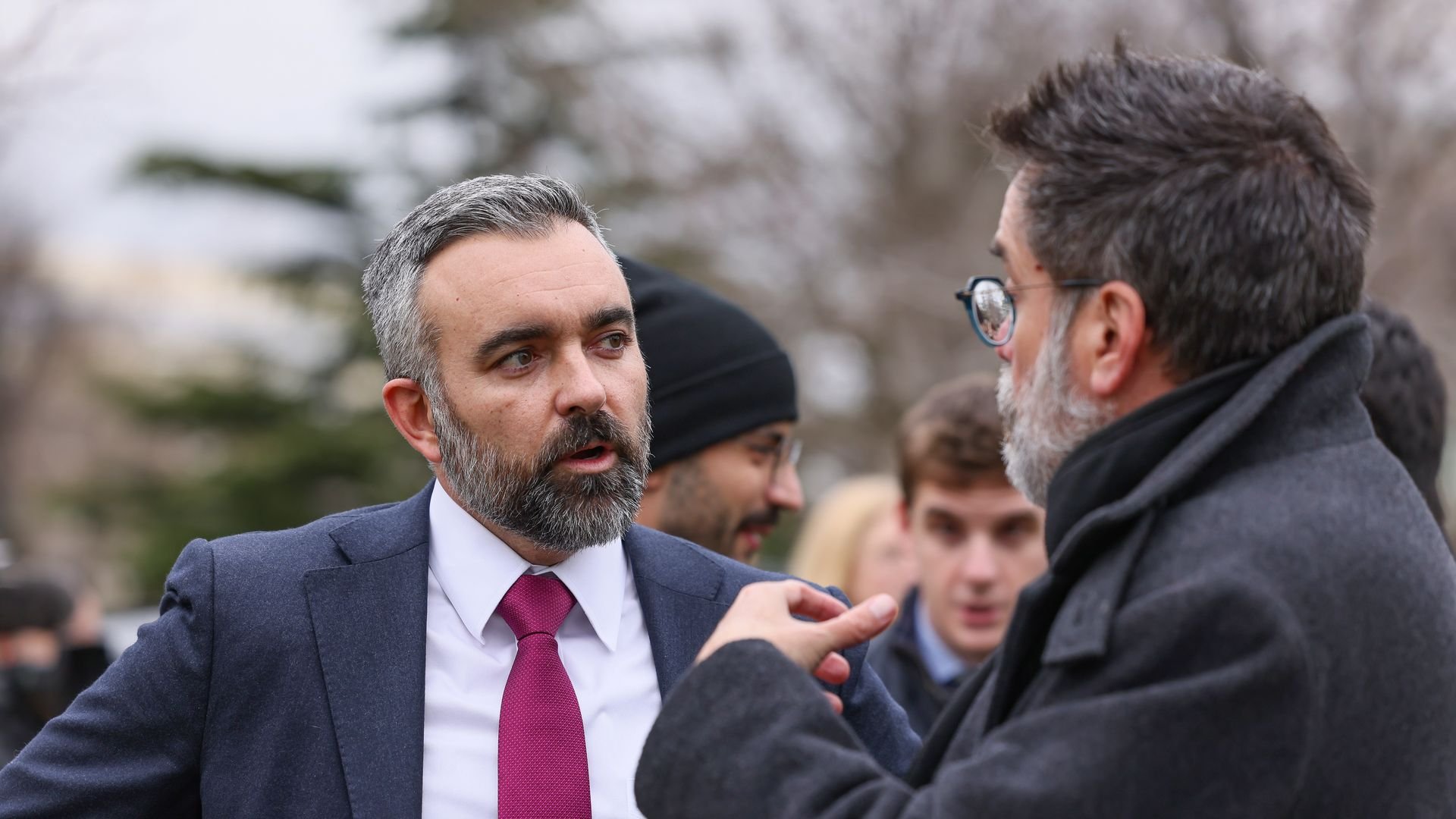 Man in red tie looks at man in black coat