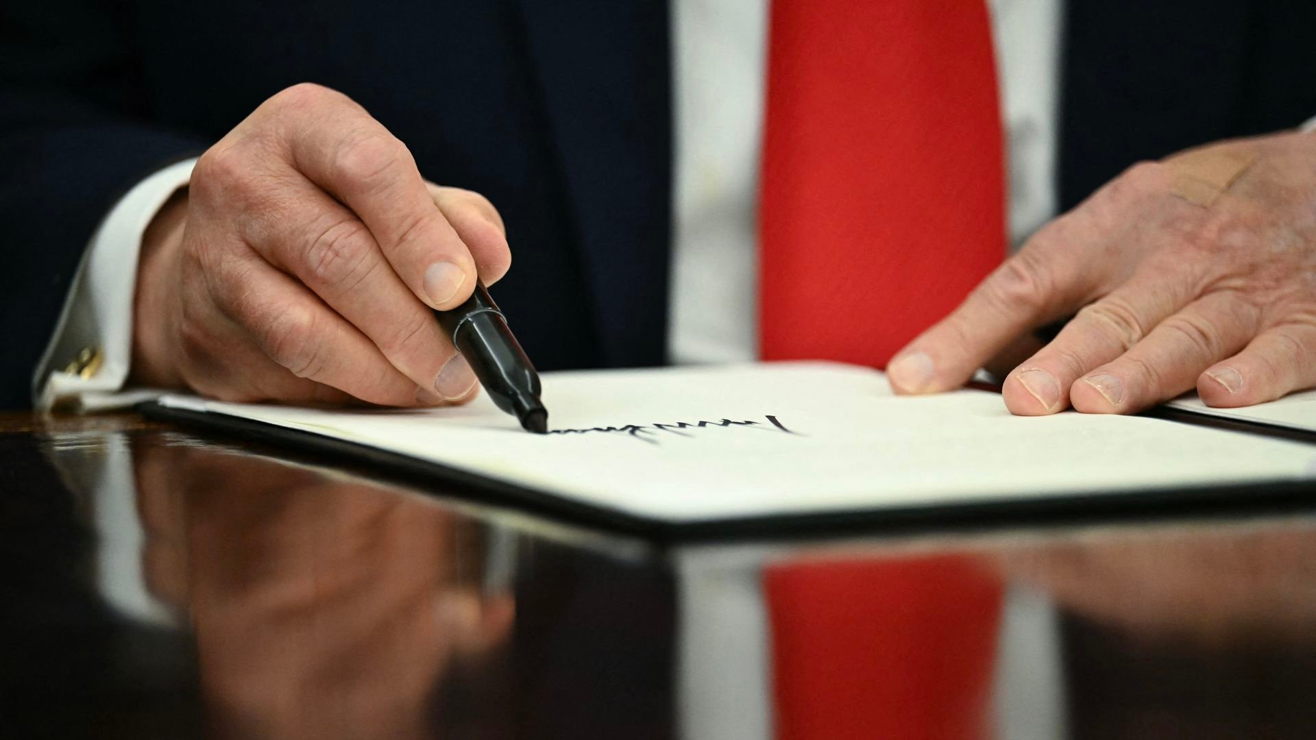 President Trump's right hand signs a document.