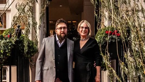 Secretscape Gavin Munro and Alice Munro standing underneath one of their chairs grown from a tree in London