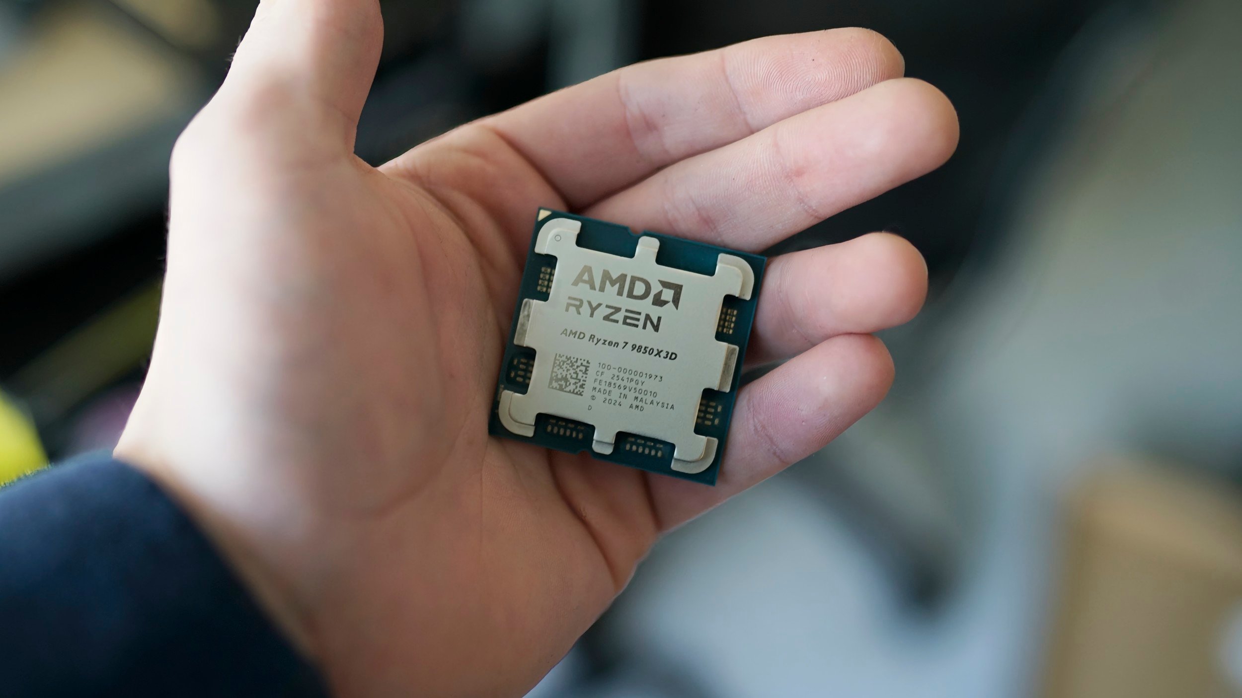 A hand holding the Ryzen 7 9850X3D.