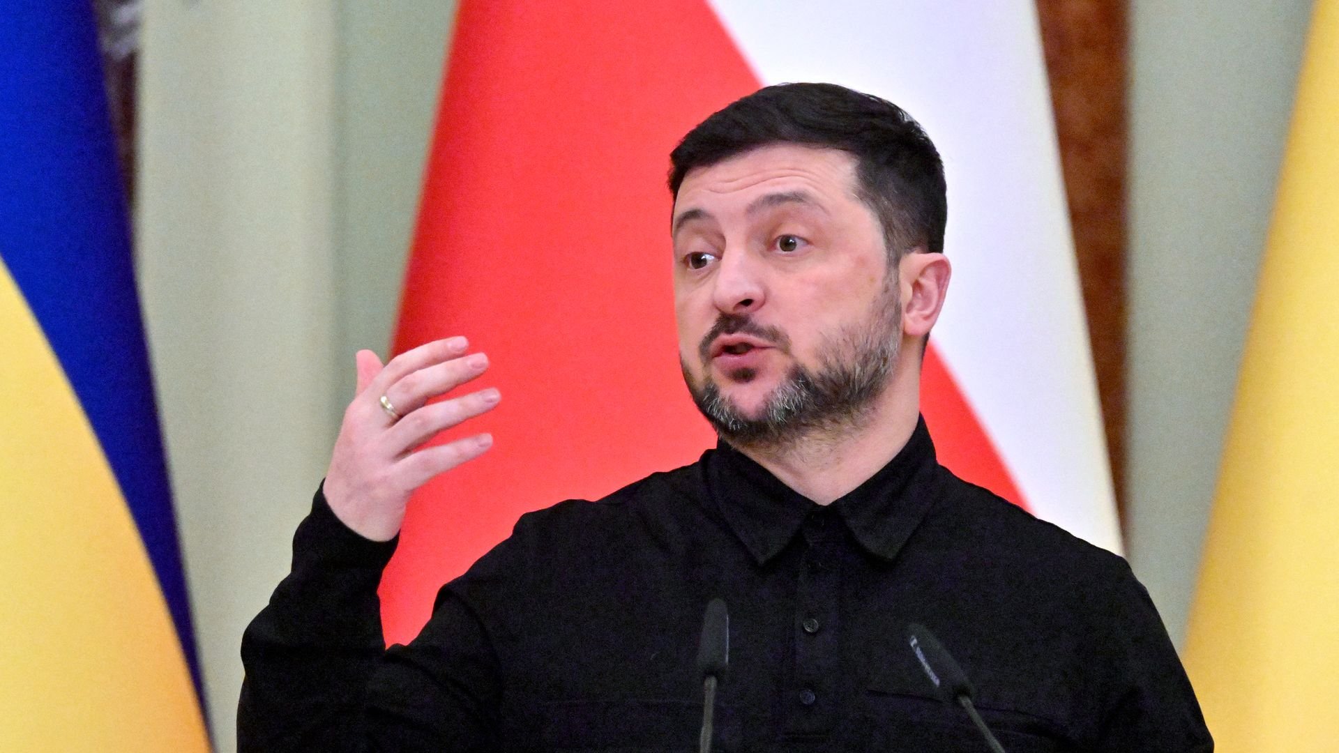 Man speaks at a podium with flags behind him